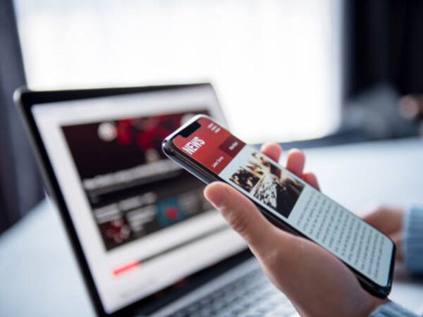 Online news on a smartphone and laptop. (Mockup website). Woman reading news or articles in a mobile phone screen application at home. Newspaper and portal on internet, copy space.